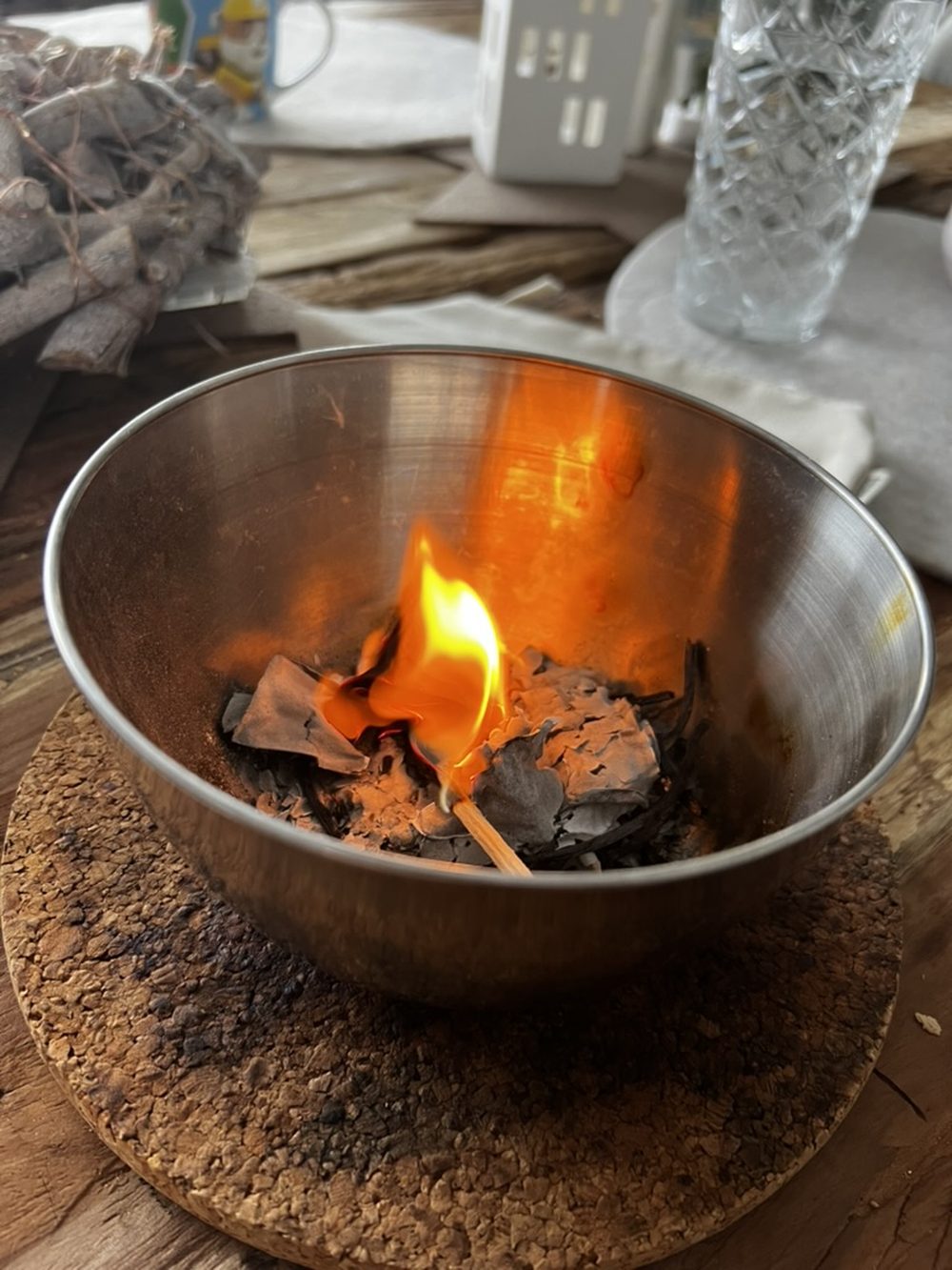 Eine Feuerschale auf einem Holztisch, in der Papier brennt